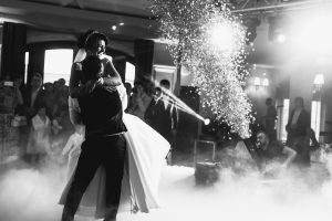 Bride and groom dancing during an elegant wedding reception with dramatic lighting and celebration effects.